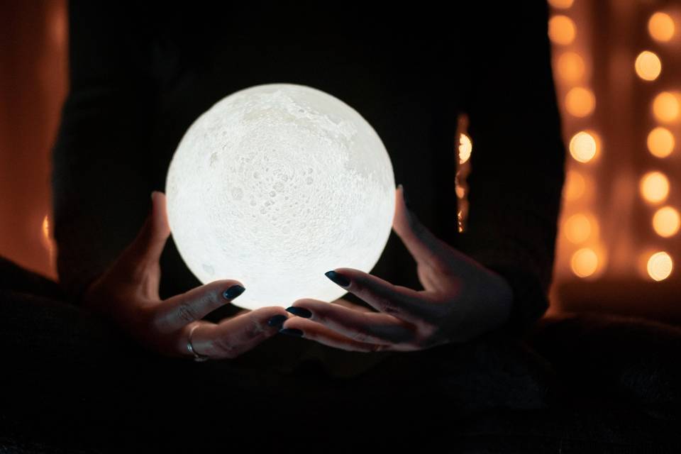 Silhouette of a person holding an illuminated moon