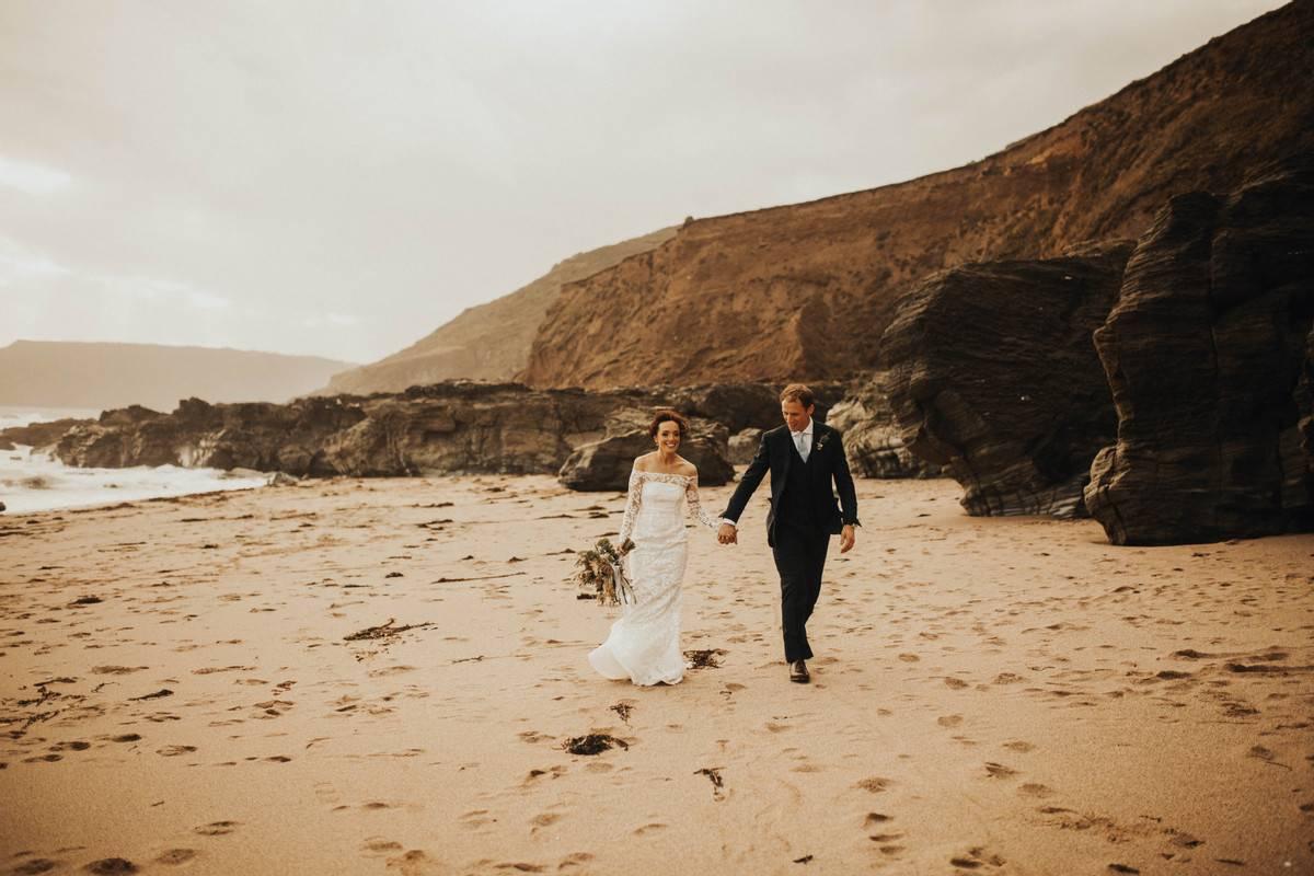 Bride and groom holding hands on a beach