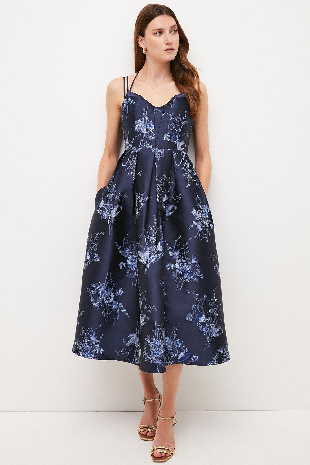 Model wearing a jacquard blue floral bridesmaid dress with a full skirt
