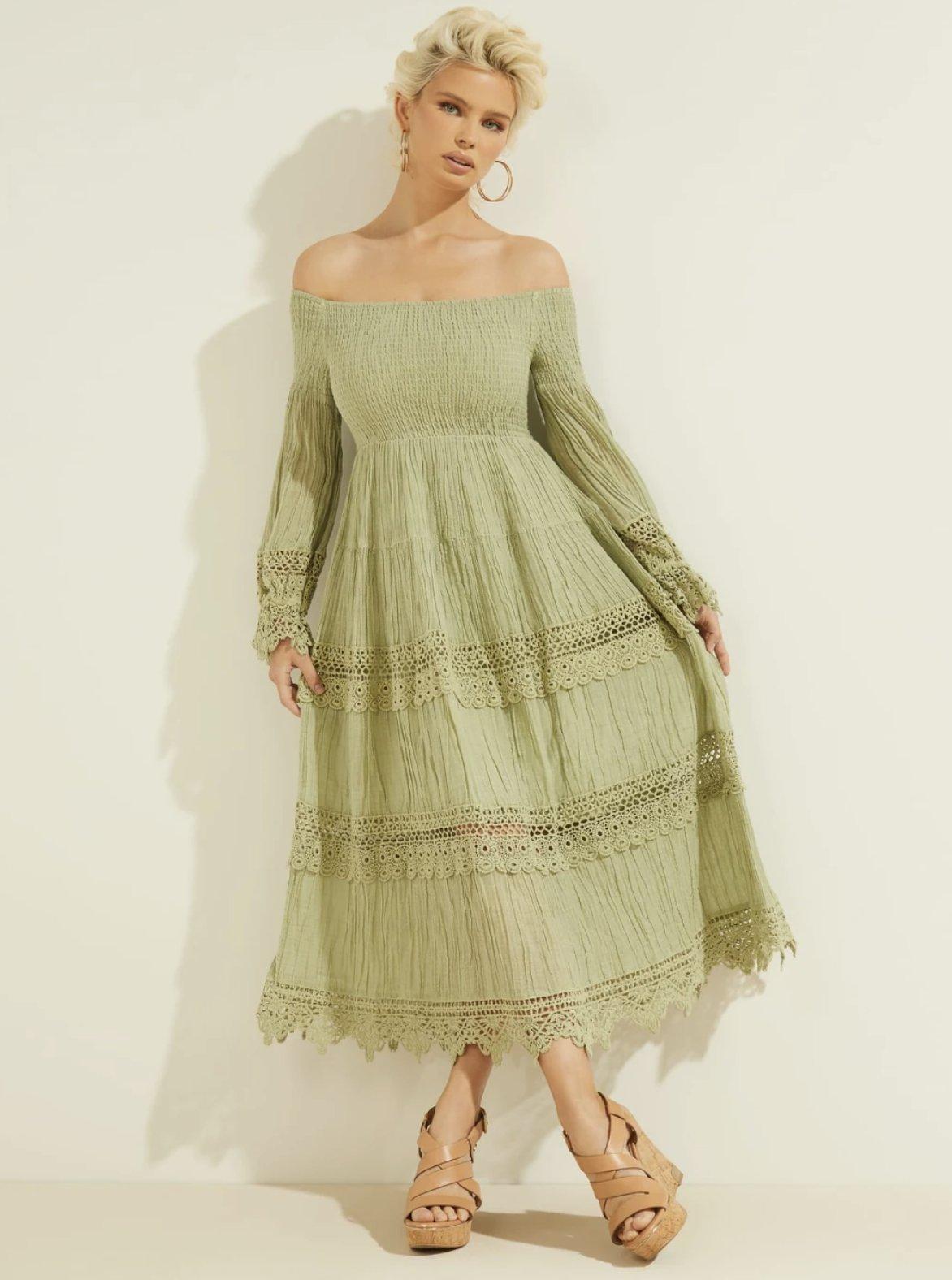 Model wearing a green midi dress with off-the-shoulder neckline and macrame details