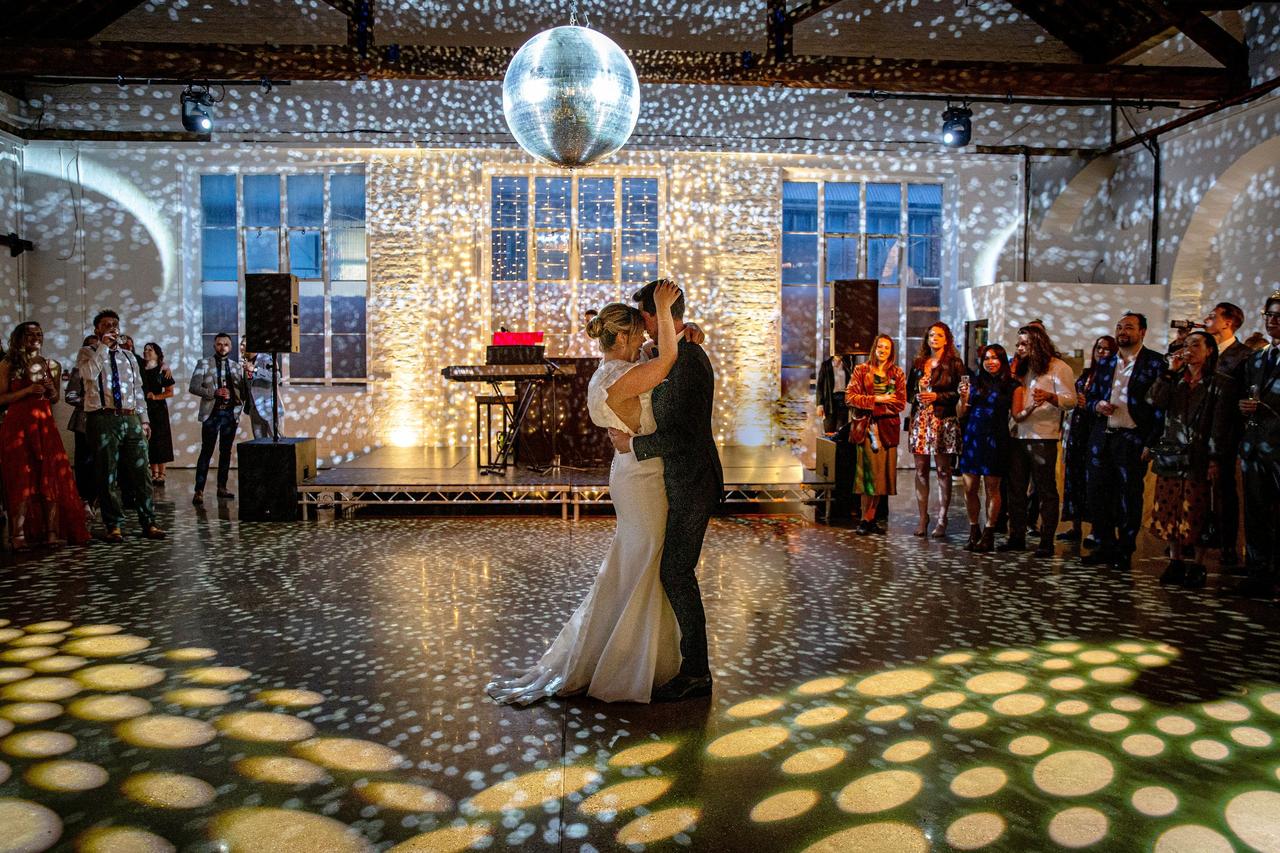 A bride and groom dance underneath a disco ball