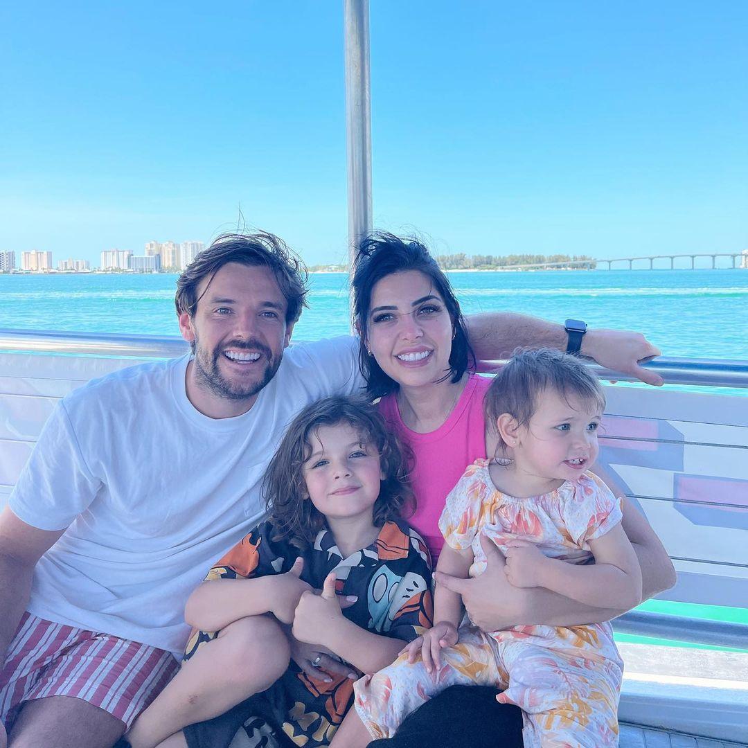 Cara and Nathan posing on a boat together with their two children on a family holiday