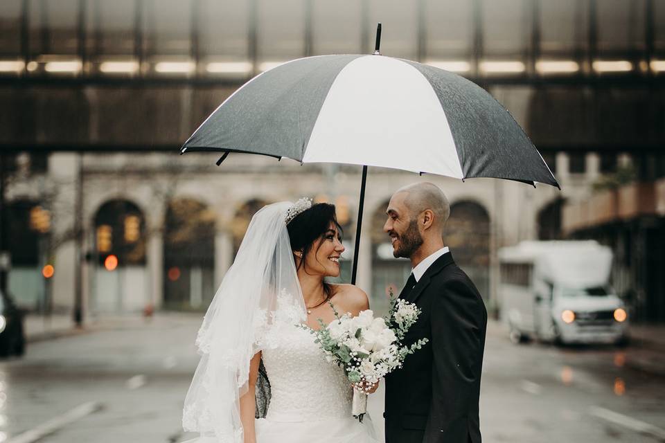 Couple at a wedding posing outdoors under an umbrella