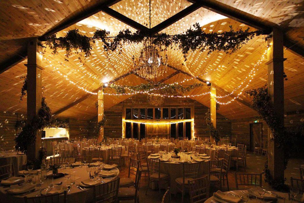 Wedding breakfast layout with exposed beam, fairy lights and foliage