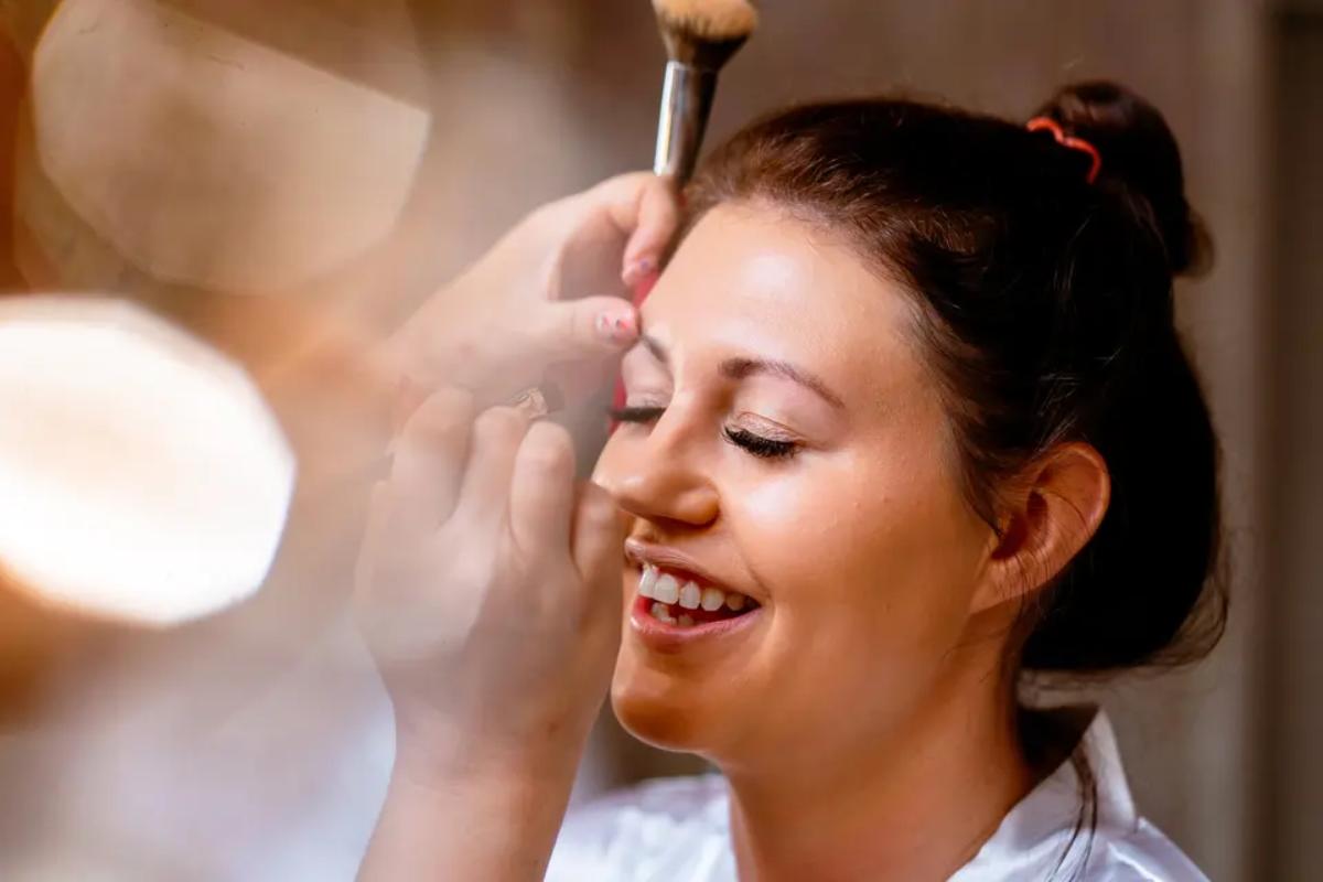 a makeup artist working on a brunette bride's makeup applying the radiant base and eyelashes - sj faces