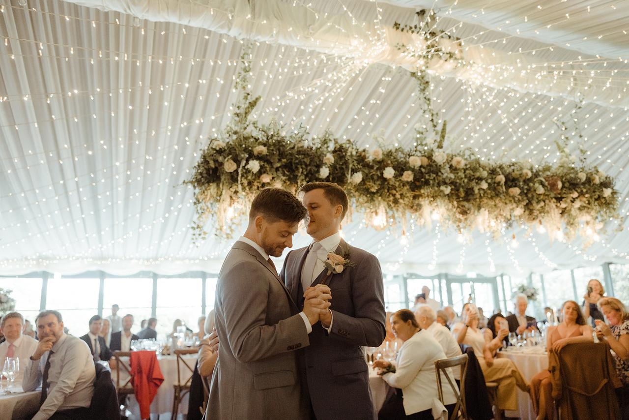 The grooms dance as the seated guests watch on\