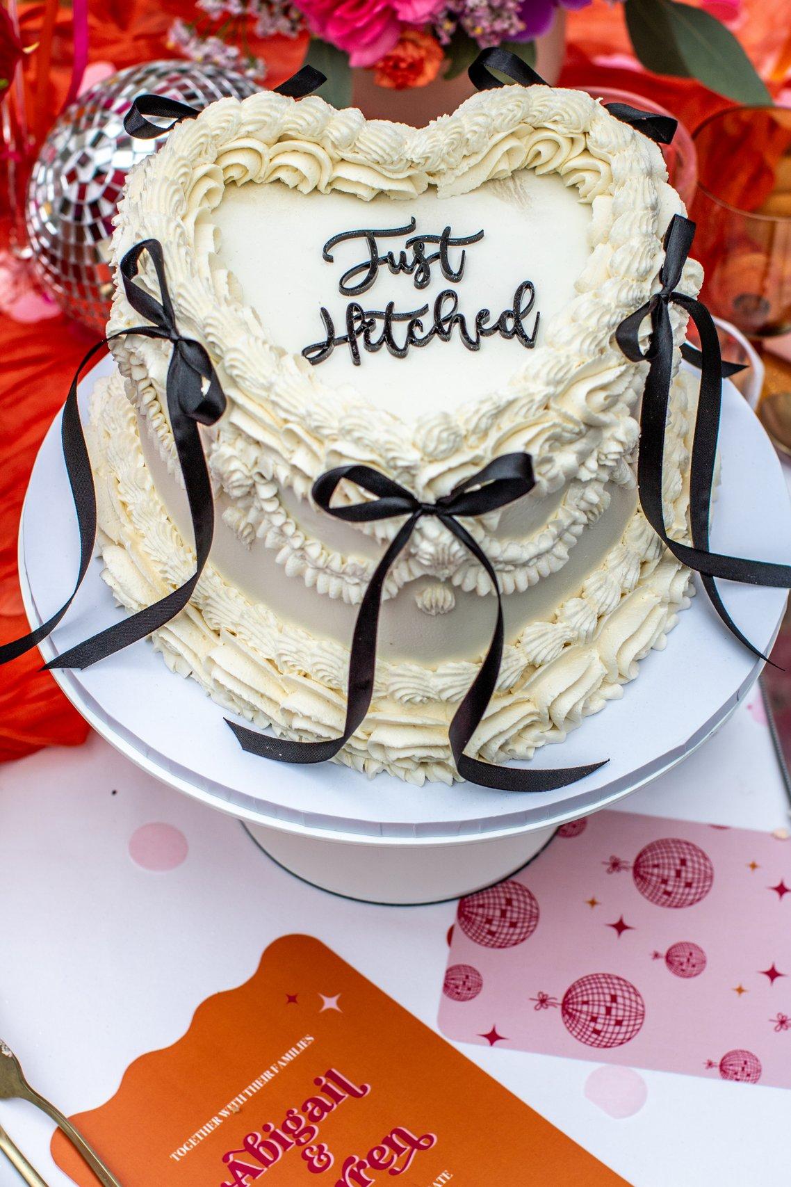 heart shaped vintage style wedding cake with 'just hitched' topper and black satin bows