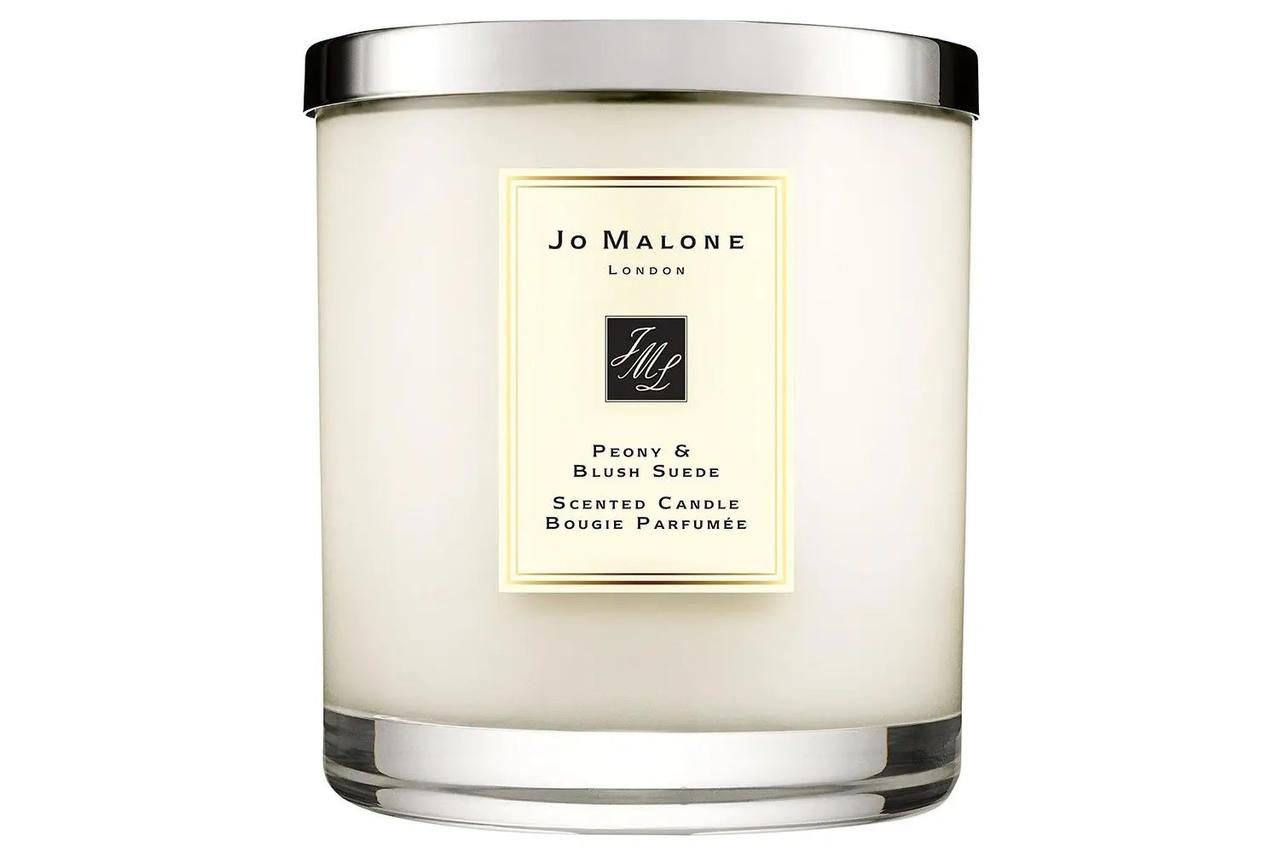 A peony and blush suede scented candle in a large glass holder on a plain background. The black label reads Jo Malone London.