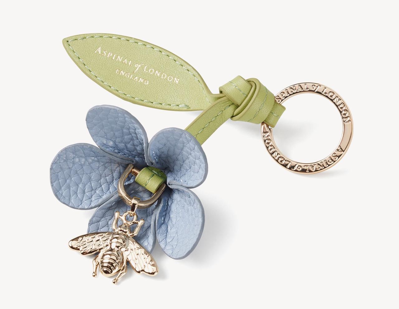A light blue and green leather wildflower keyring with metal bumblebee attached.