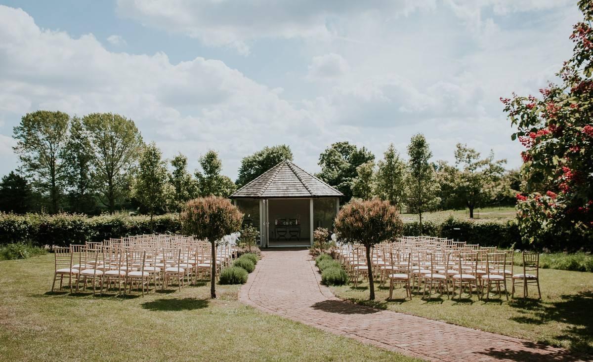 an outdoor pavillion wedding set up on a manicured lawn with a brick path going through the middle
