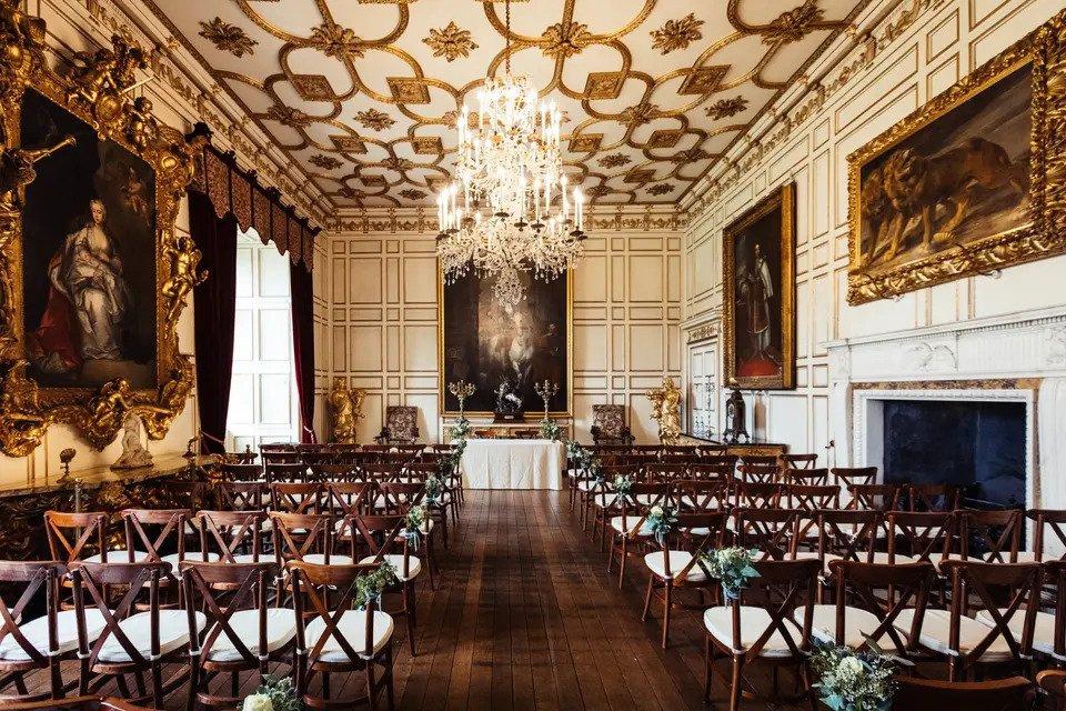 Interior room of Warwick castle with a chandelier and gold furnishings, set up for a wedding ceremony