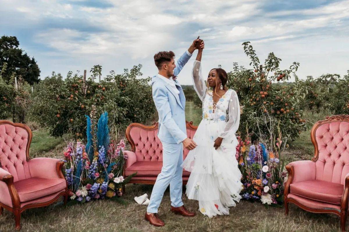 https://cdn0.hitched.co.uk/article/5039/3_2/1280/jpg/139305-14-a-groom-wearing-a-lght-blue-wedding-suit-twirls-a-bride-around-in-front-of-three-pink-velvet-arm-chairs-outdoors.jpeg