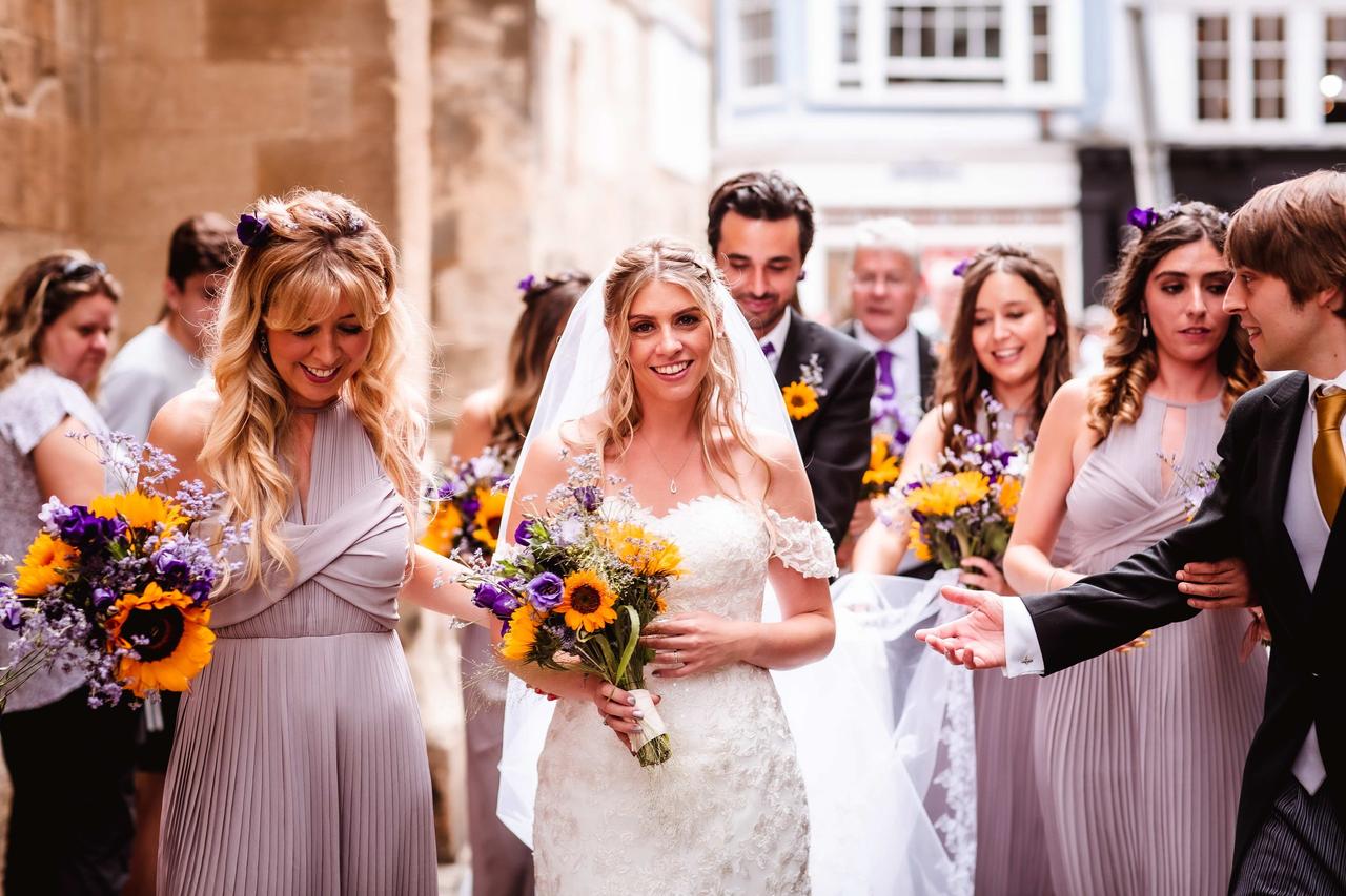 The bride and groom walk down the street surrounded by their bridesmaids