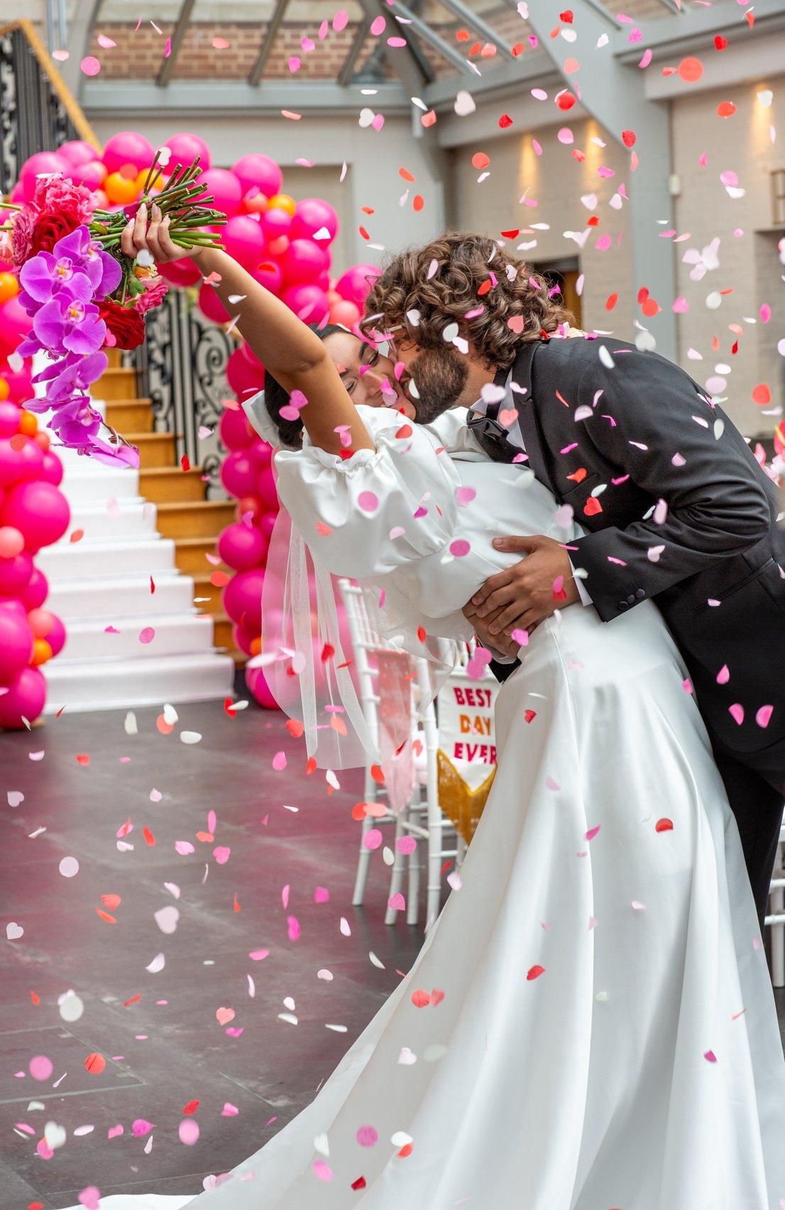 Couple kissing as confetti cascades around them