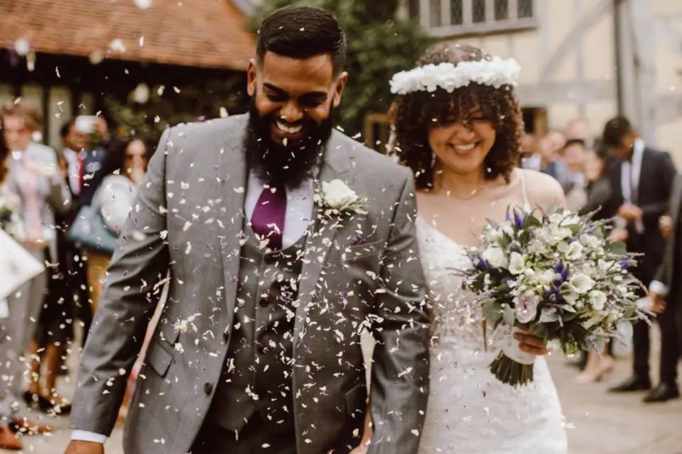 a bride and groom exiting their wedding ceremony as guests throw white confetti over them