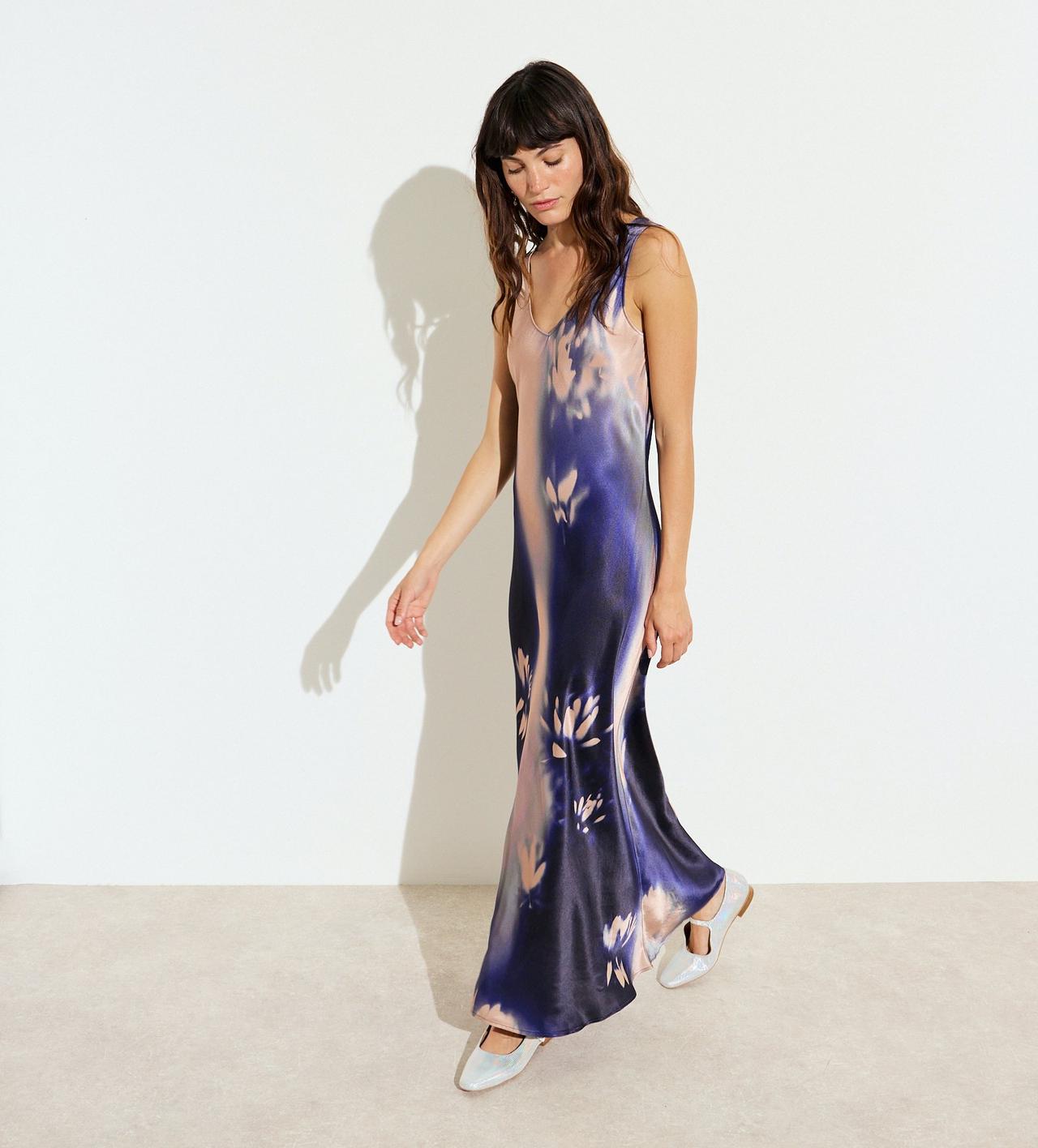 A wedding guest wearing a maxi-length satin slip dress with a dark blue and pale pink floral print.