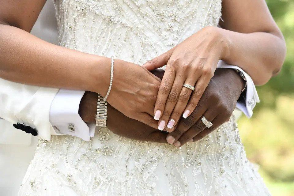 Close-up shot of a bride and groom's hands while they embrace