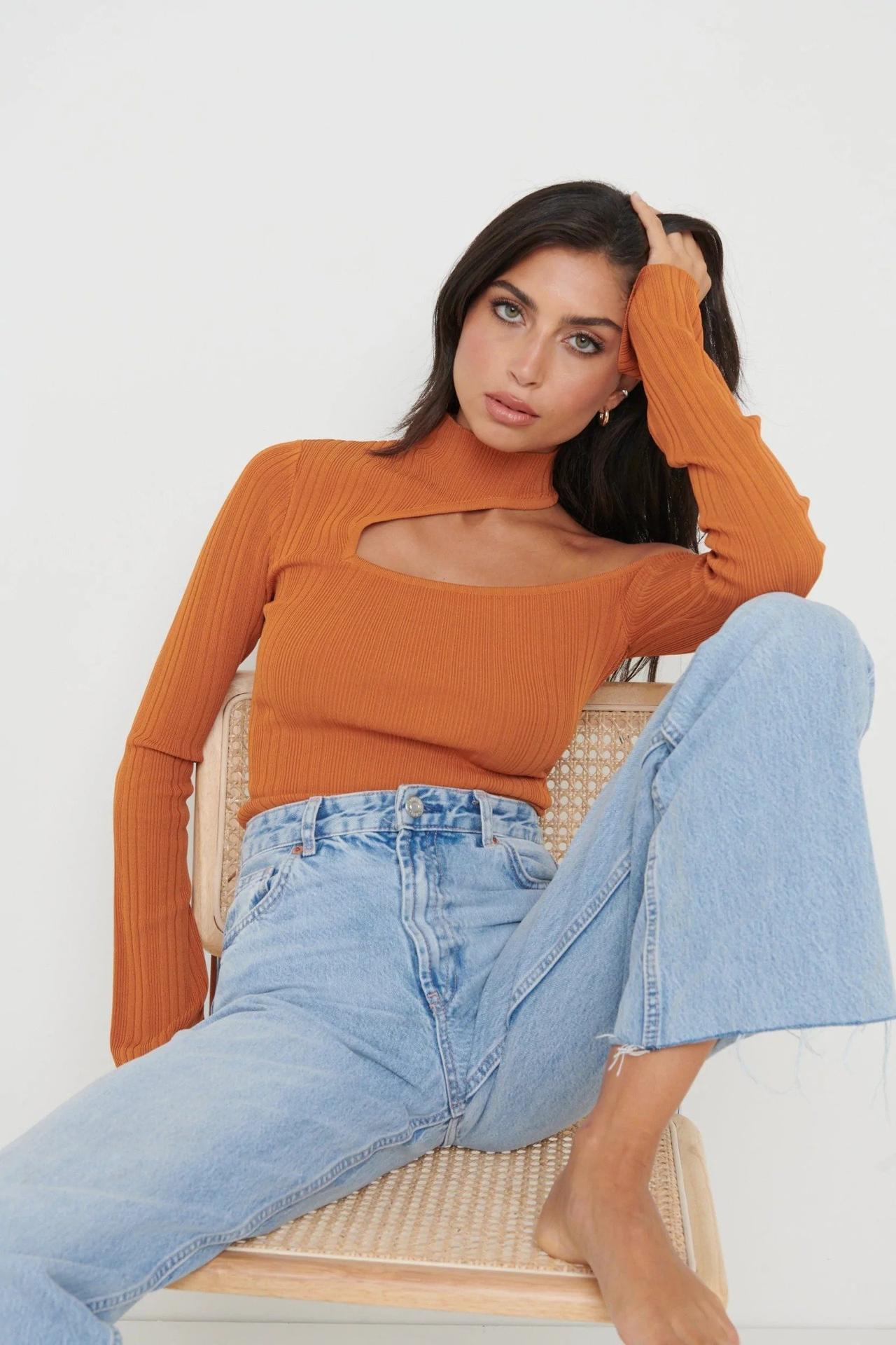 Model wearing an orange knit jumper and blue jeans