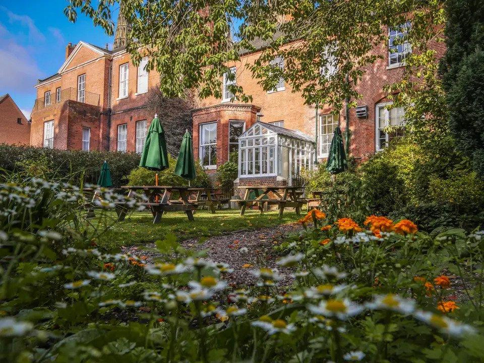 Red brick house with conservatory, picnic table and flowers