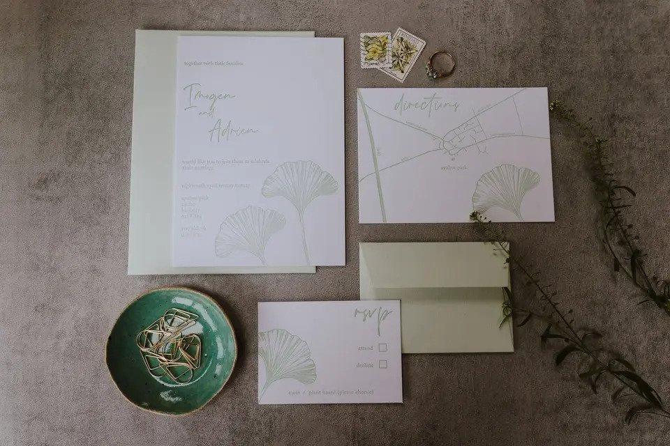 Elegant sage wedding invitation on a table with three parts: invite, map and RSVP