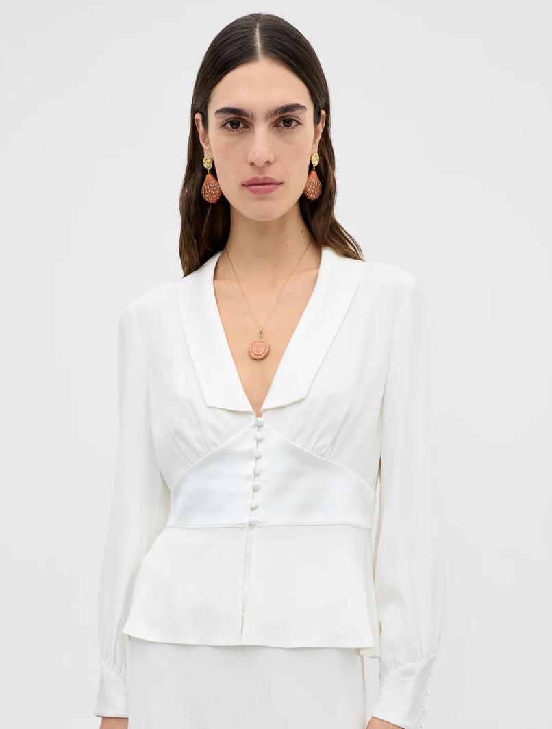 a white tailored shirt with fabric buttons from Rixo, styled by a model with large strawberry earrings
