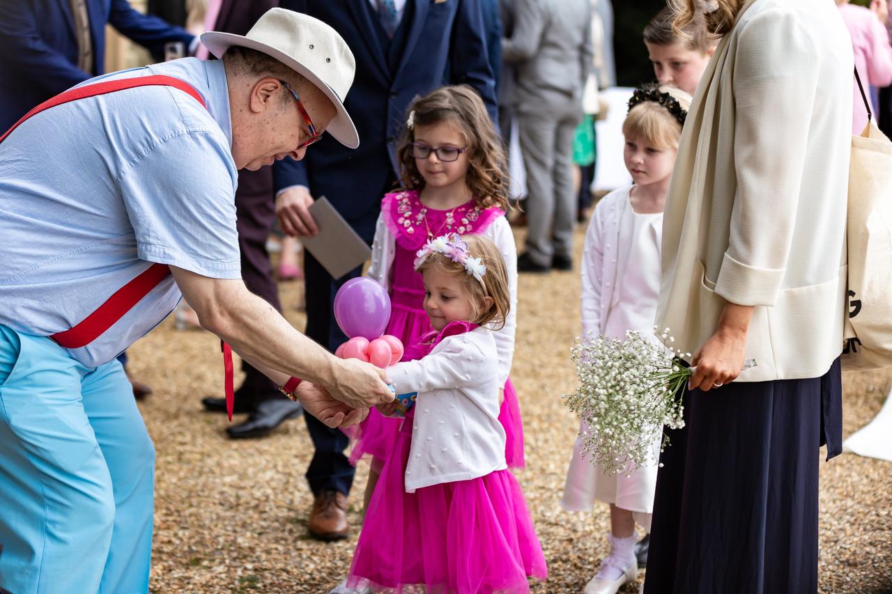 A children's wedding entertainer giving a little girl a flower made of balloons at a wedding