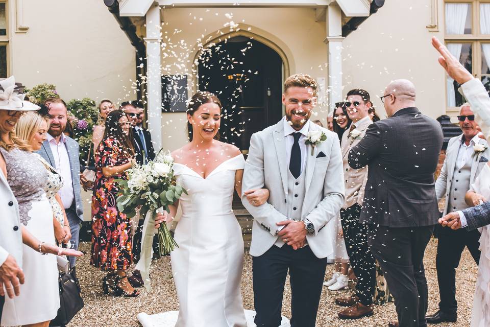 Newlywed bride and groom leaving a hotel wedding venue to a shower of confetti