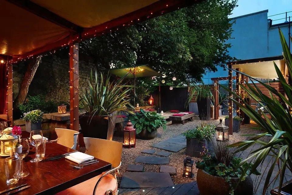 Courtyard with plants, fairy lights, pillar candles in lanterns and restaurant tables