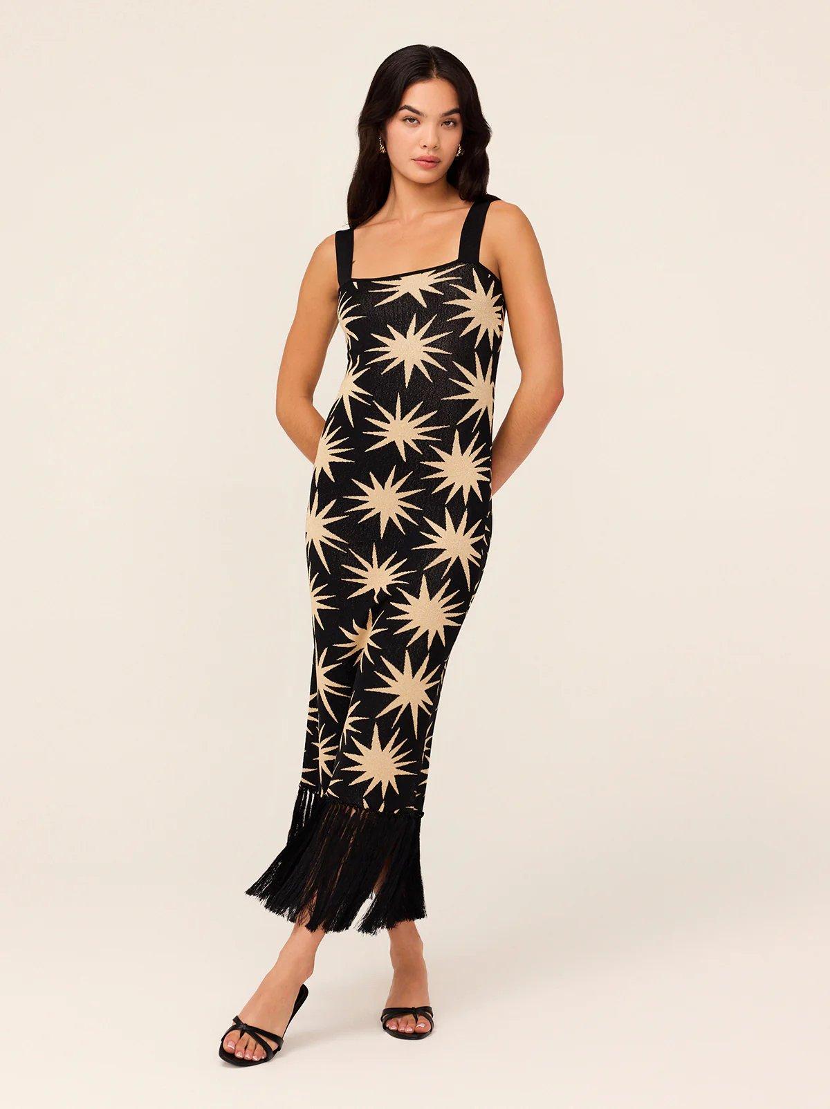 a wedding guest wearing a lurex knit dress in black with an all-over star print and fringing on the hem.