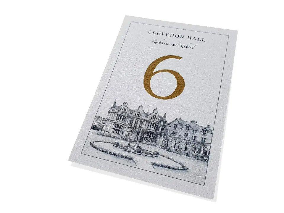 Black and white table number with hand drawn venue and gold number 6