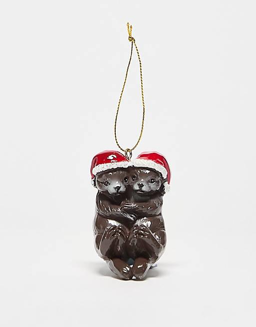 A chistmas tree decoration with two otters hugging each other wearing christmas hats