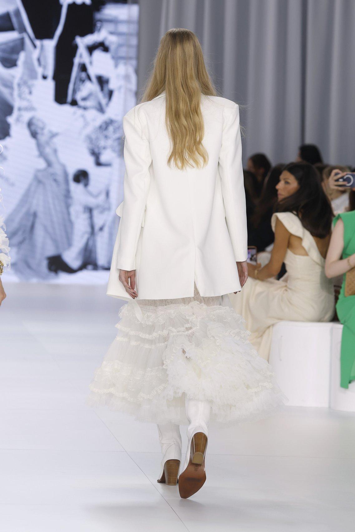 model styled by Yolancris walking back down the runway in a short, bohemian wedding dress and white blazer