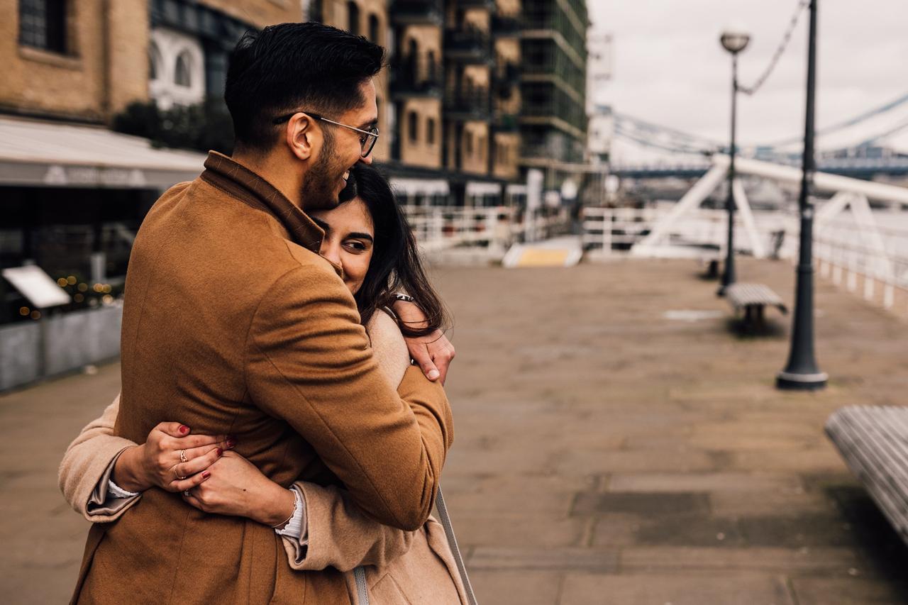 A couple embrace on the banks of the Thames