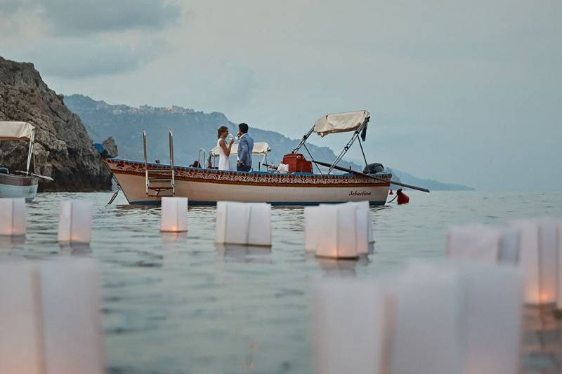 Couple on a boat in the ocean with floating lanterns