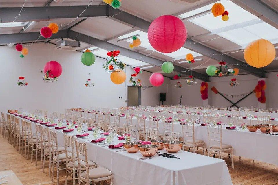 Wedding meal room with long tables and multicoloured lanterns