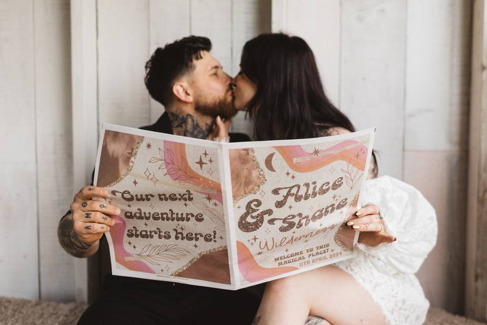 couple kissing whilst opening a wedding newspaper announcing their engagement