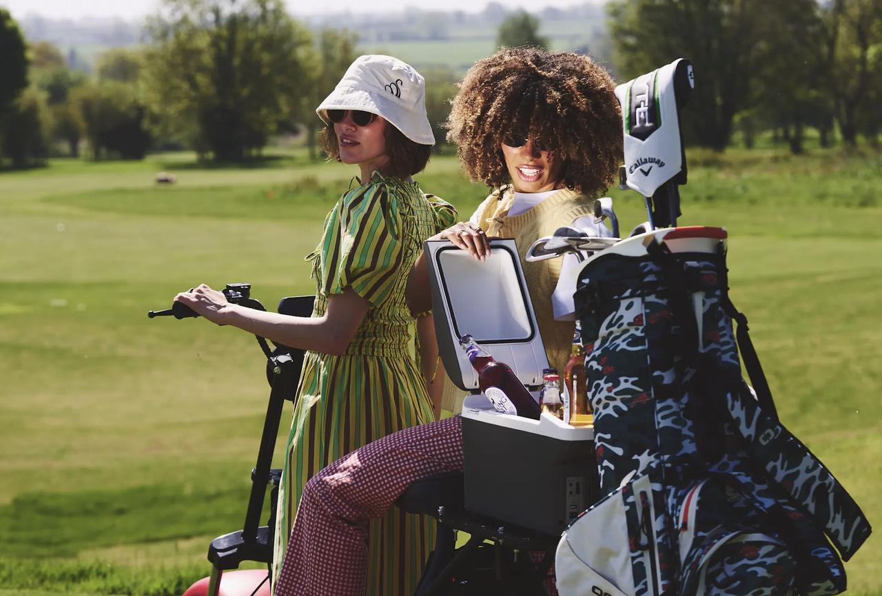 two women driving a golf cart across a golf course