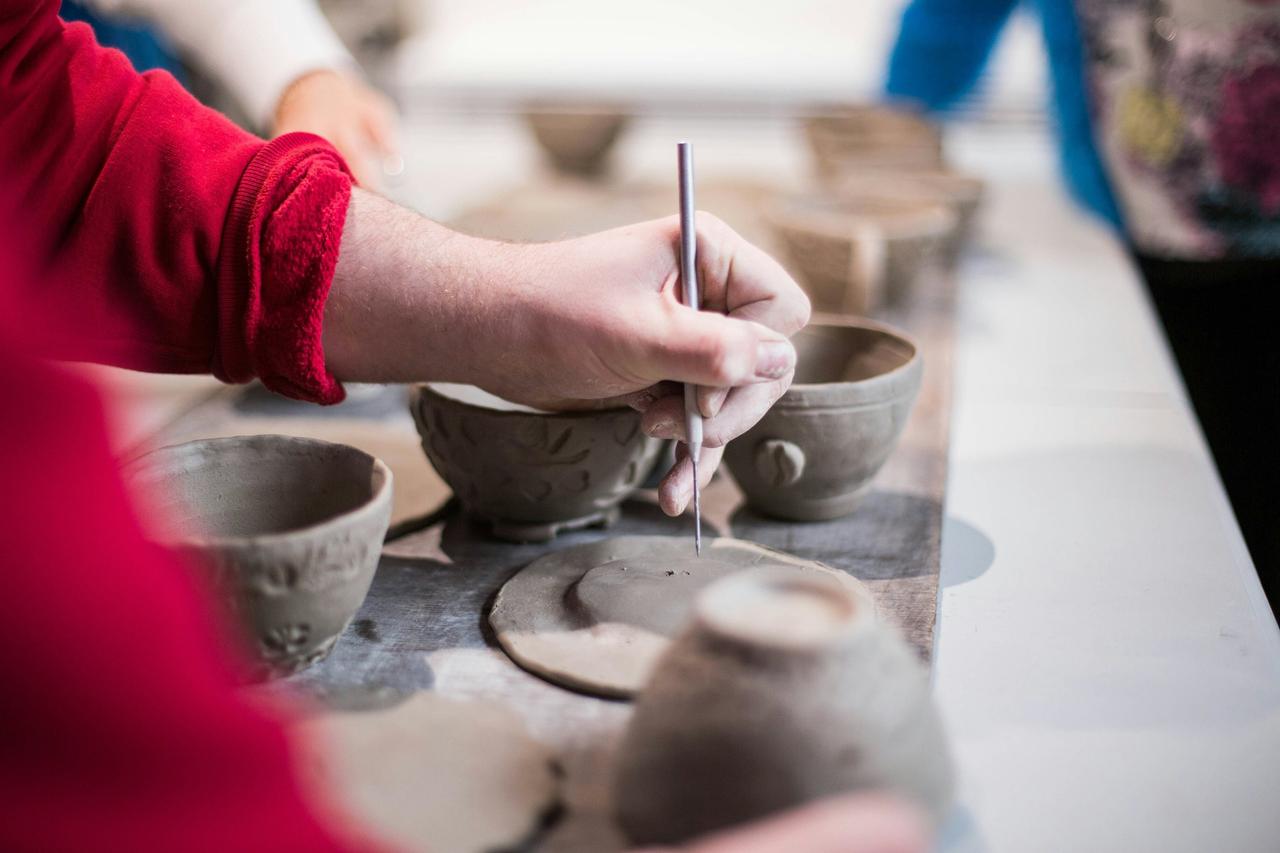 hand painting a pot in a ceramic pottery class
