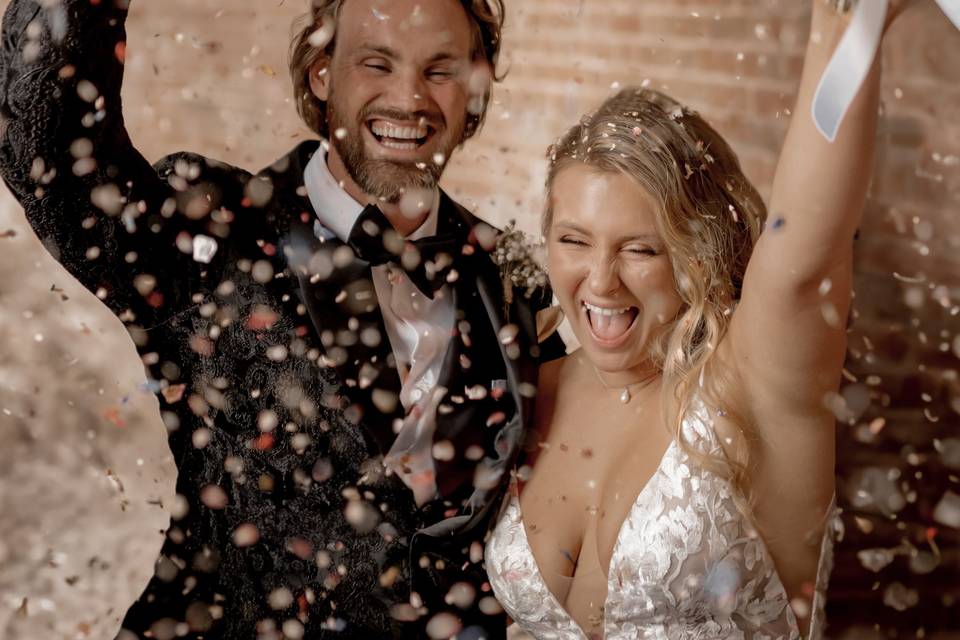 Influencer Sophie Lait and her husband Bryn laughing on their wedding day as confetti falls in front of them