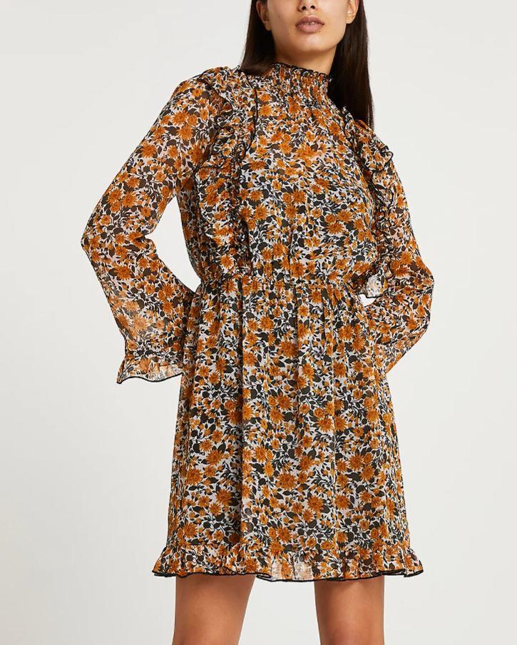 Model wearing a long-sleeved brown floral ruffled dress with a high neck and tiered hem