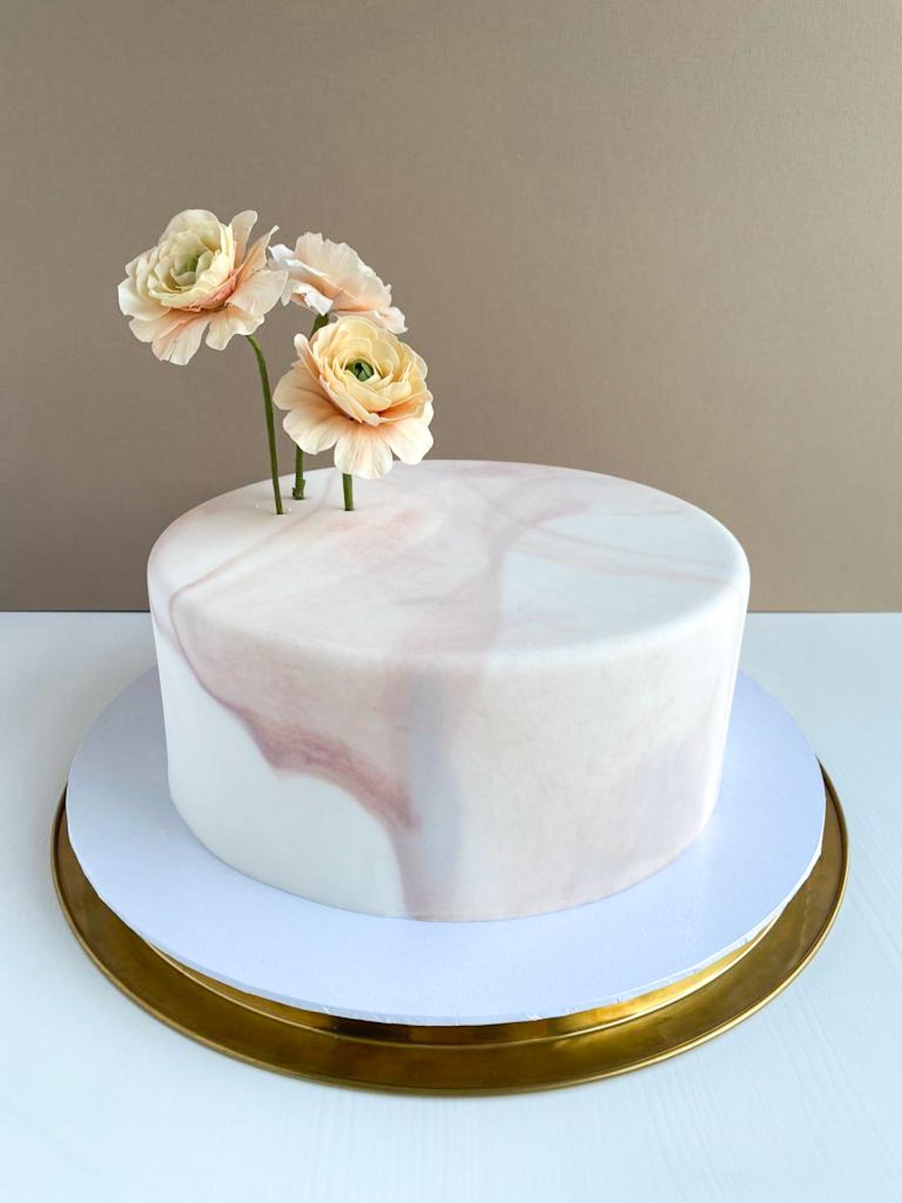 A single tiered marble iced wedding cake with iced flower stems.