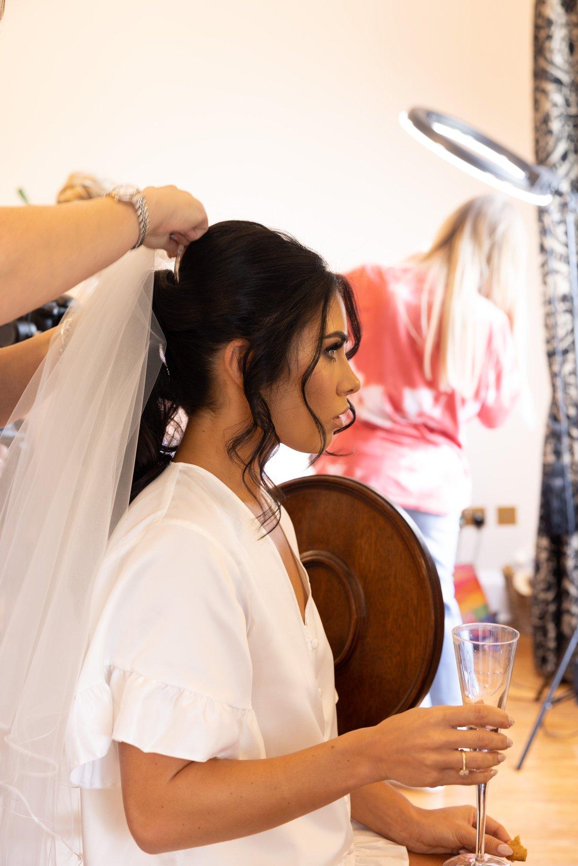 a bride has her veil adjusted on the morning of her wedding