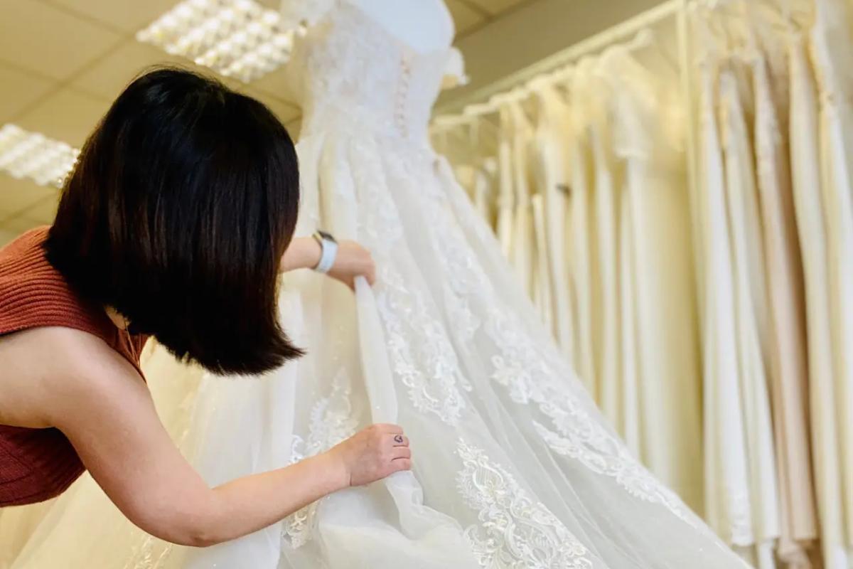 miss he a seamstress making adjustments to a wedding dress, shot from below looking up