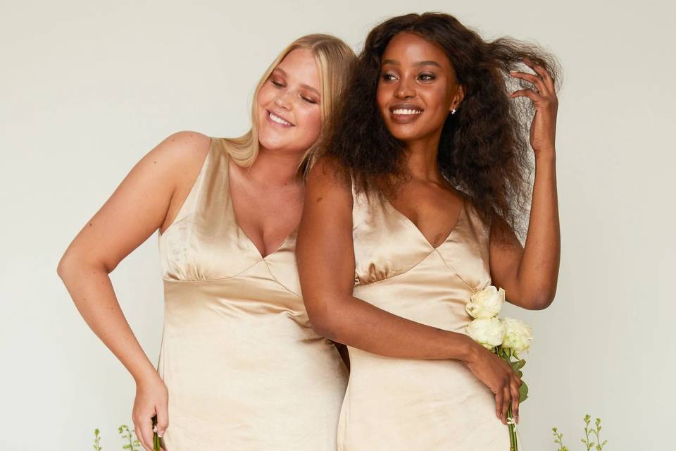 Two models wearing satin gold bridesmaid dresses