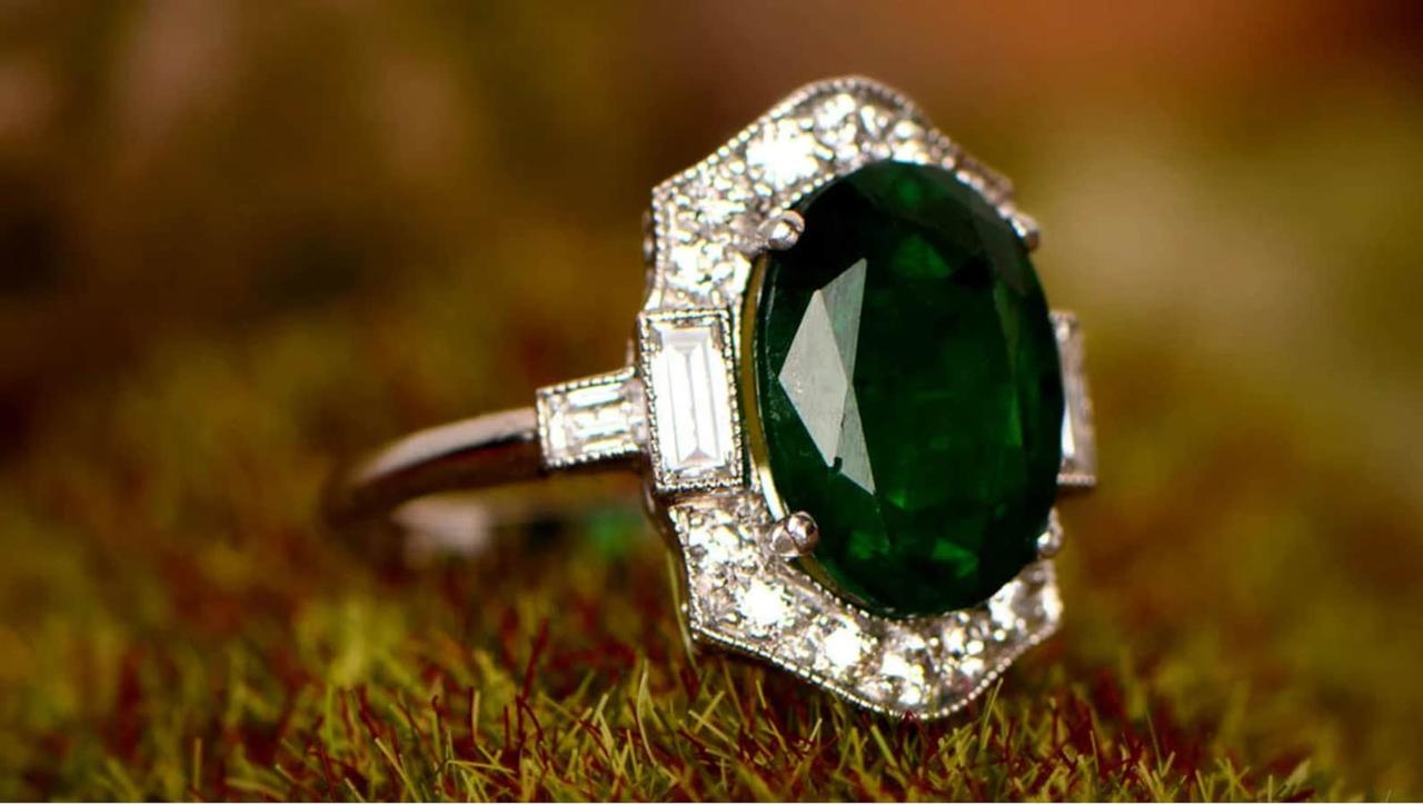 Art deco style oval emerald ring encircled with clear gems on a silver band