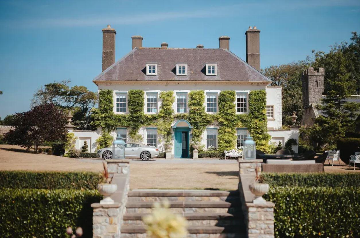 a picture of the outside of a white wedding venue with ablue door and a car outside