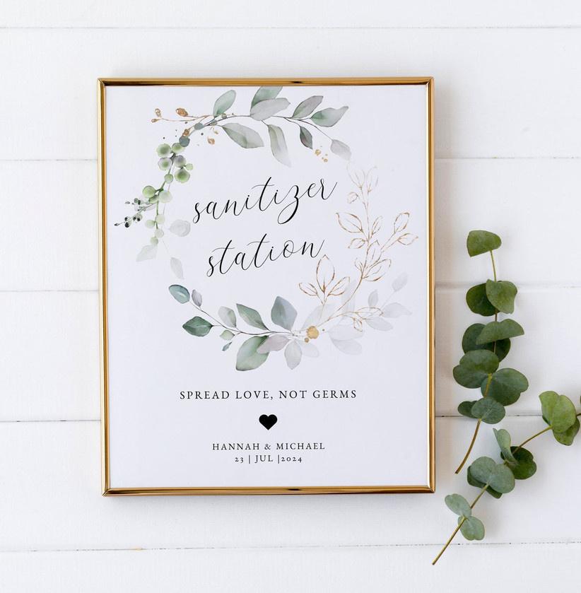 White sign with eucalyptus saying 'sanitiser station' for a wedding