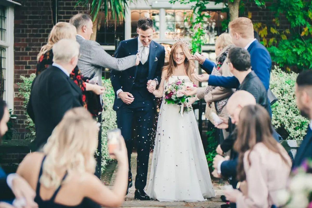 guests greet and celebrate the newly married couple as they walk to exit their wedding ceremony