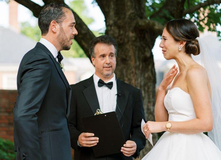 a bride is emotional at the altar standing opposite her husband with a celebrant inbetween them