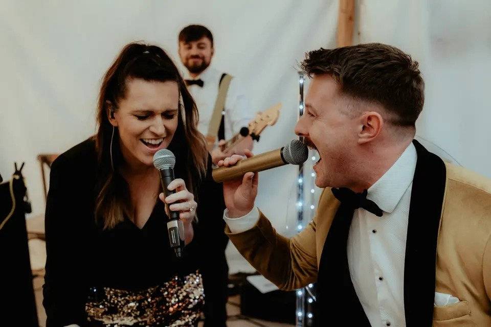 close up shot of two singers from a wedding band with microphones